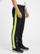 Side view of Maania Wears black baseball pants featuring a wide neon yellow vertical stripe and black turf shoes.